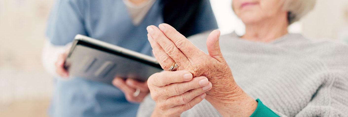 Elderly patient demonstrating her arthritis in her hands to her doctor