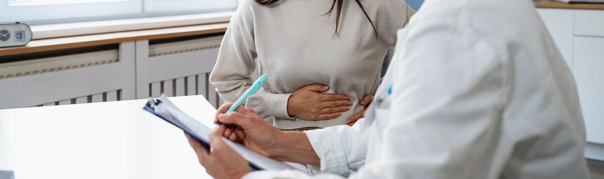 Patient holding stomach and talking to doctor about pain levels